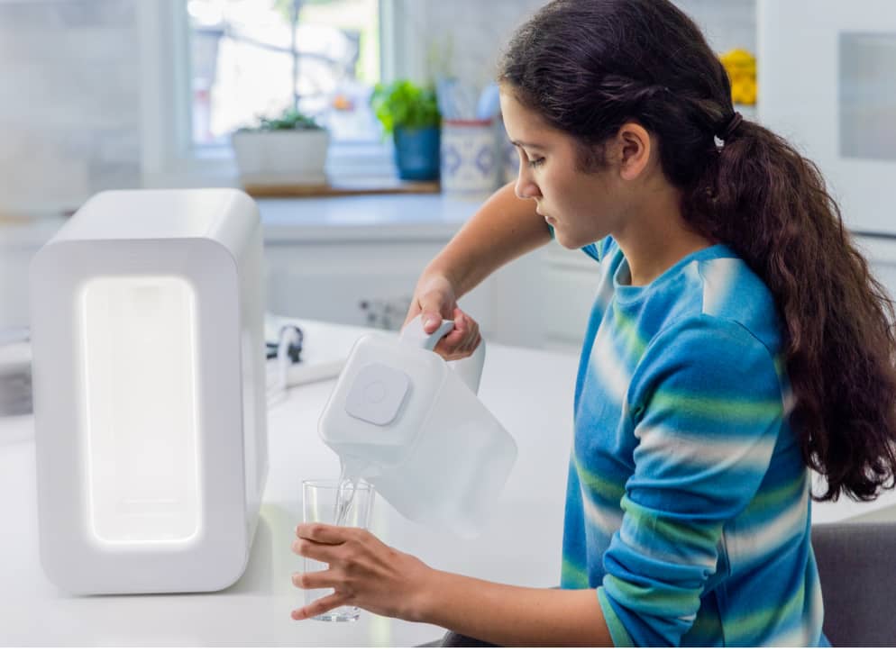 girl pouring a glass of water from spout pitcher